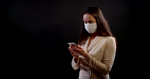 Portrait of a Woman on a Black Background. She's Wearing a Disposable Face Mask, Standing Three