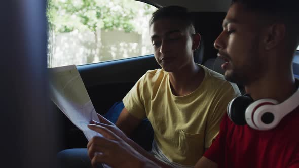 Two mixed race friends using map and talking in cab