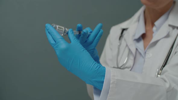 Closeup Hands in Medical Gloves Filling Syringe with Vaccine Indoors