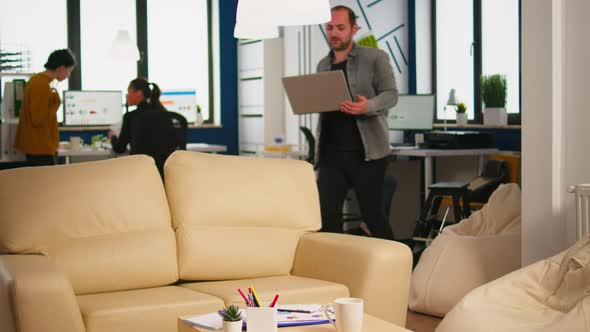 Business Man Typing on Laptop Sitting on Couch in Start Up Office