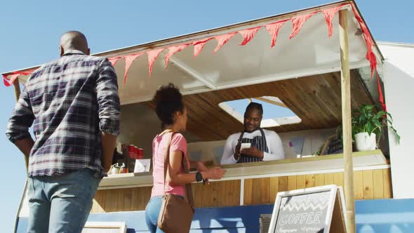 African american man wearing apron taking order from a woman at the food truck