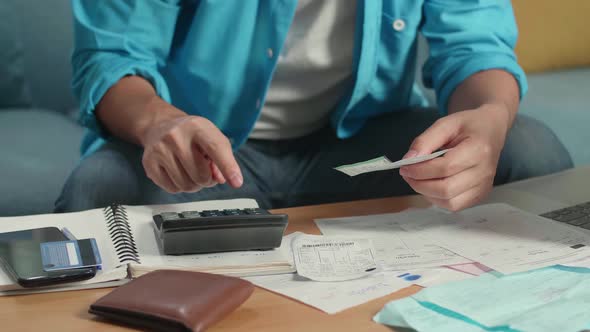 Close Up Of Man's Hand Holding Bill And Calculate Money By Calculator