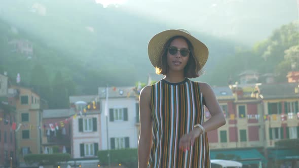 A woman with watch, hat, sunglasses, striped dress traveling, Portofino, Italy, luxury resort Europe