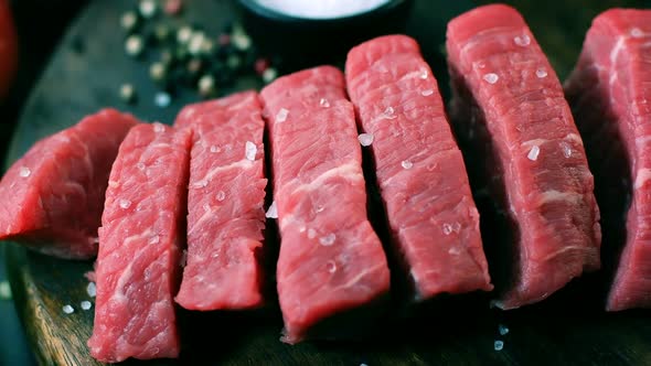 Fresh raw beef fillet, cutted on steak pieces on a wooden board, dolly shot