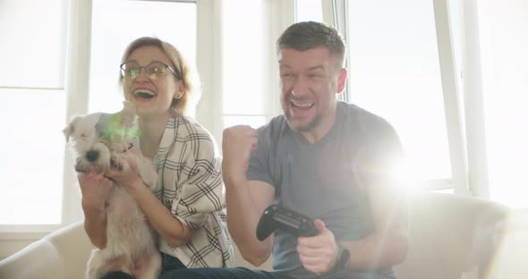 Happy Couple Sitting on the Sofa and Playing Video Games Using Controllers in Love Have Fun Playing