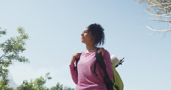 Smiling biracial woman looking away and hiking in countryside