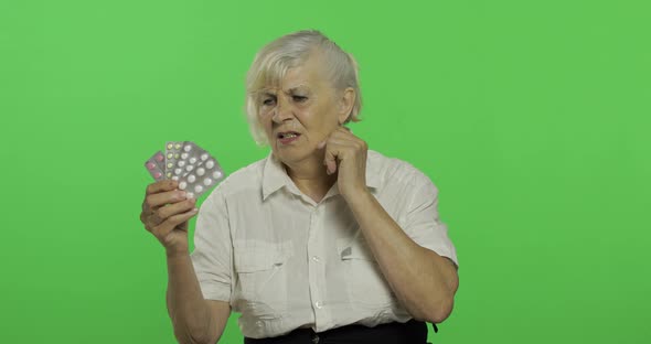 An Elderly Woman Dissatisfied Looking at Blister Pills. Chroma Key
