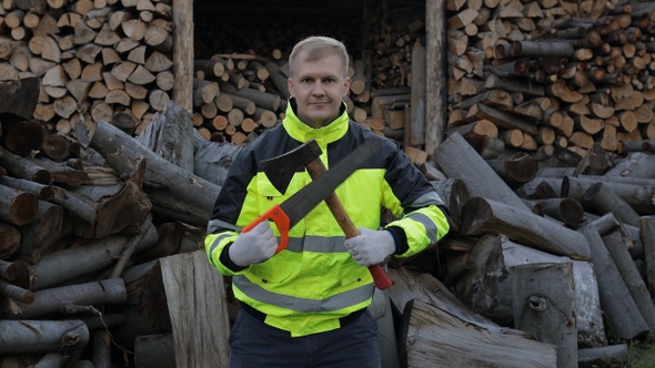 Lumberjack in Reflective Jacket. Man Woodcutter Holds Small Axe and Saw on His Hands. Firewood