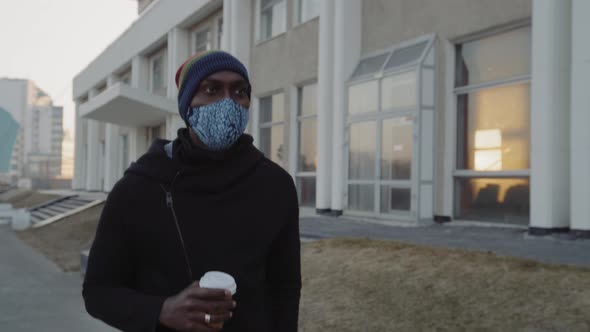 African American Man Out and About in the City Streets During the Day, Wearing a Face Mask Against