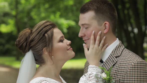 Newlyweds. Caucasian Groom with Bride Making a Kiss in Park. Wedding Couple. Man and Woman in Love