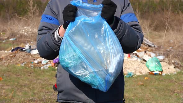 a Volunteer Holds a Garbage Bag in Front of Him