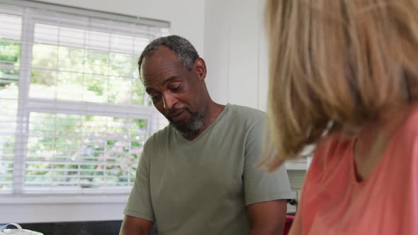 Happy diverse senior couple preparing food in kitchen and talking