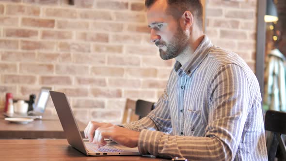 Beard Casual Man working on Laptop in Loft Place