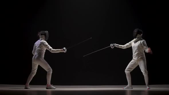 Duel of Two Female Fencers on Black Background