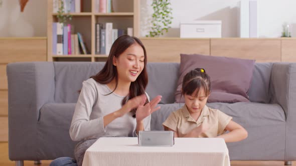 Happy asian mother and daughter sing a song and dancing together watching music video apps in smartp