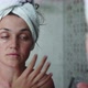 Young Woman is Applying Cream on the Face Eye Area in Bathroom Looking at Mirror - VideoHive Item for Sale