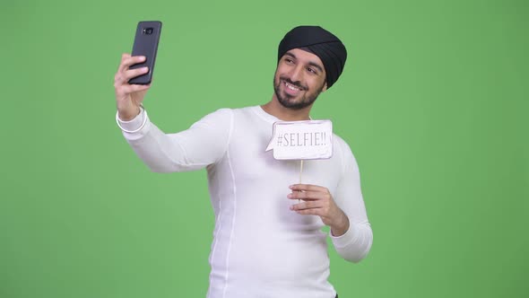 Young Happy Bearded Indian Man Taking Selfie with Paper Sign