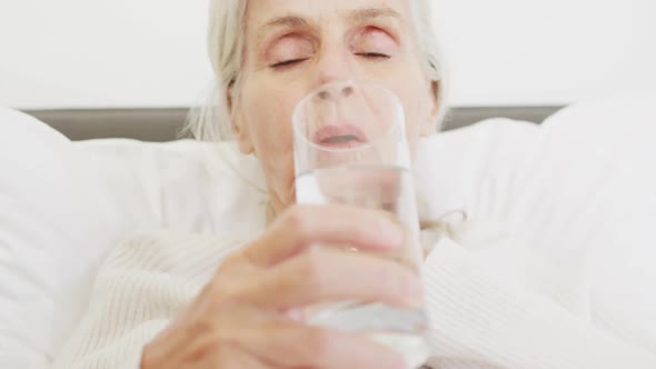 Video of caucasian senior woman drinking water in bed