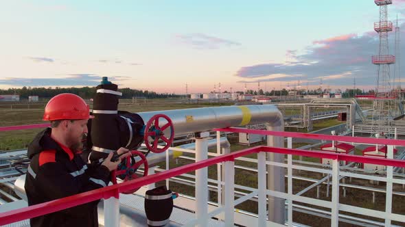 An Employee of the Oil and Gas Industry on Tanks for Cleaning Oil From Gas Turns Off the Valve at