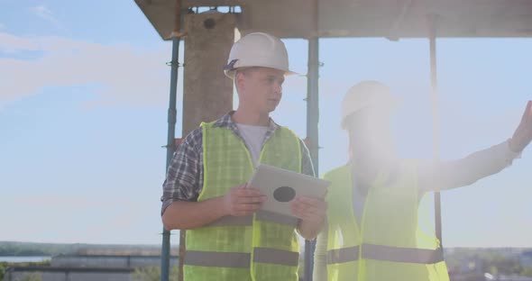 Construction Worker Man and Architect Woman in a Helmet, Discuss the Plan of Construction of House