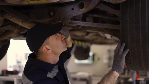 Car Service Worker Examinating Car Fails with Lighter in Hands