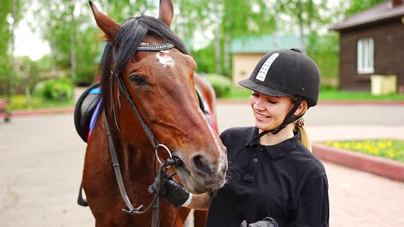 Lovely Young Woman Wearing Helmet Stroking to Her Brown Horse