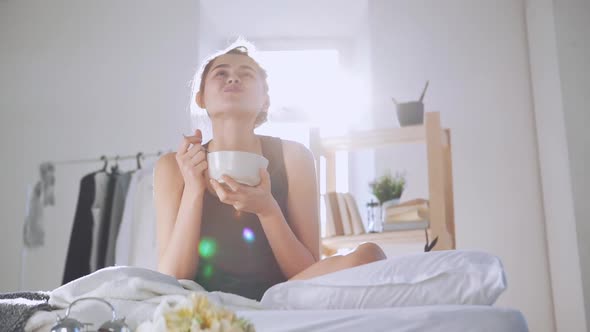 Happy Caucasian Girl Eating Breakfast in Bed in Slowmotion