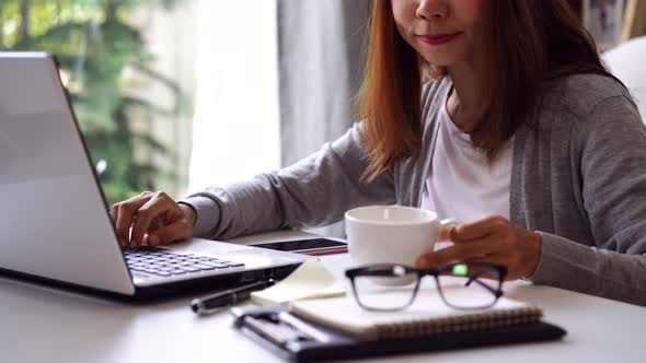 Young woman sitting at living room and working on laptop and smartphone