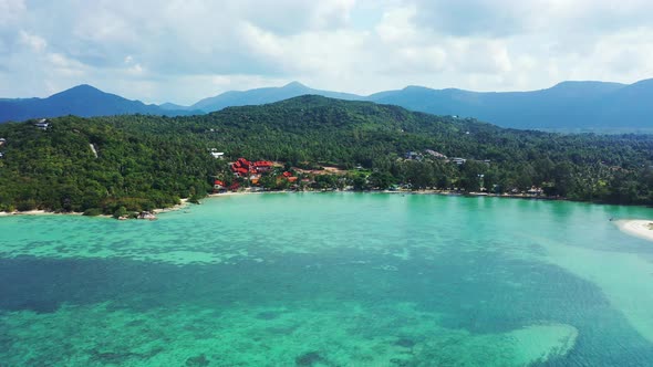 Beautiful seascape with shoreline of tropical island full of green vegetation washed by calm turquoi