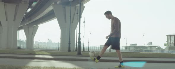 Footballer Juggling Soccer Ball on City Street
