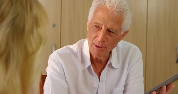 Senior man with digital tablet interacting to senior woman