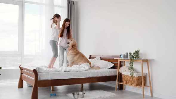 Girls Jumping in the Bed with Golden Retriever Dog