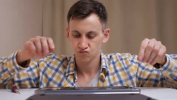 Man Removes the Bottom Cover of the Laptop and Examines the Insides