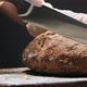 Chef in Gloves Cuts Lump of Tasty Rye Bread Loaf on Board - VideoHive Item for Sale