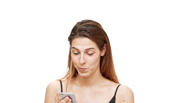 Young Beautiful Girl Looking at Phone Smiling Over White Background