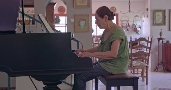 Old woman playing a grand piano at her home