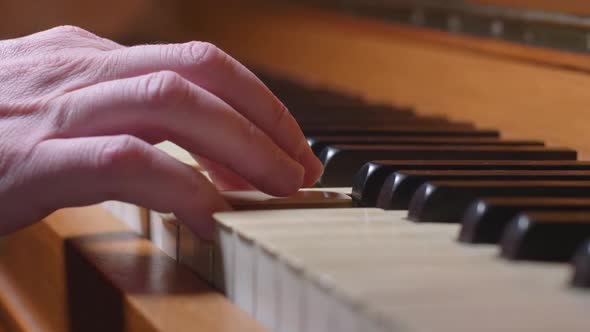 Dolly In On A Hand Playing One Chord On A Vintage Piano