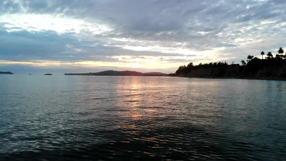 Aerial drone shot at sunset flying low over the water and reflections of the Pacific Ocean surface w