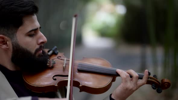 Closeup Portrait of a Male Musician with a Thick Beard Playing a Violin on the Street