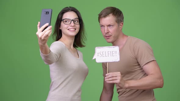 Young Happy Couple Taking Selfie Together Against Green Background