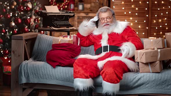 Confident Male Santa Claus Discussing Talking Smartphone at Christmas Tree