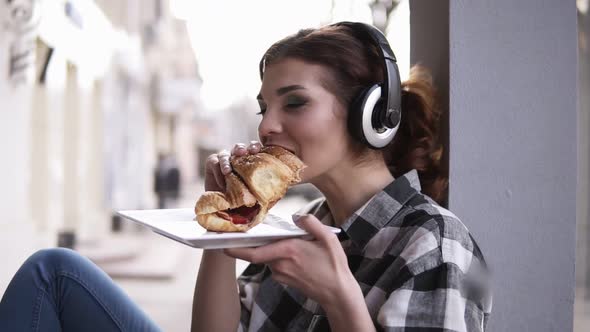 Beautiful Young Woman Sitting Next to the Window in Big Headphones