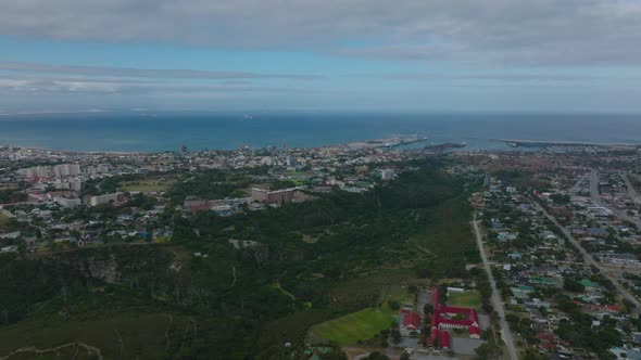 Aerial View of Green Valley with River Between Urban Neighbourhoods and Sea in Background