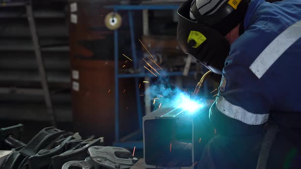 Welder in a helmet soldering metal