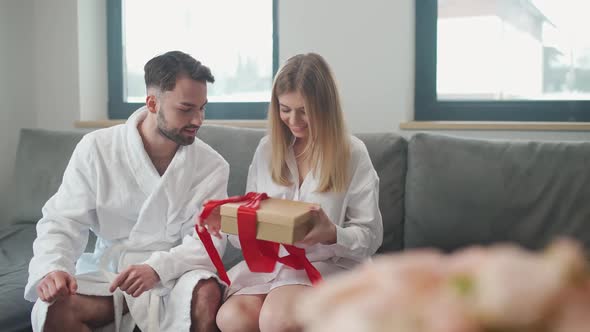 Romantic Holiday Guy Gives His Girlfriend a Box with Gift a Young Couple is Sitting in the Living