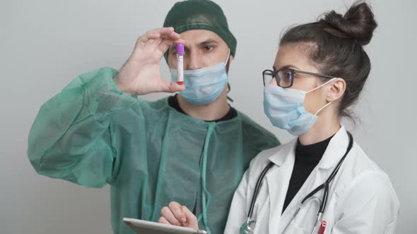 Surgeon And Doctor Looking At Patient Blood Sample and Tests