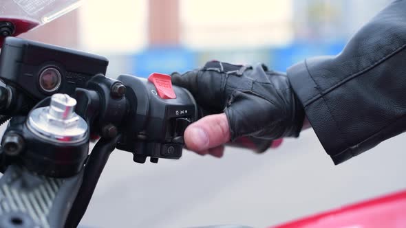 biker puts his hand on the gas handle on the motorcycle, turns on the ignition