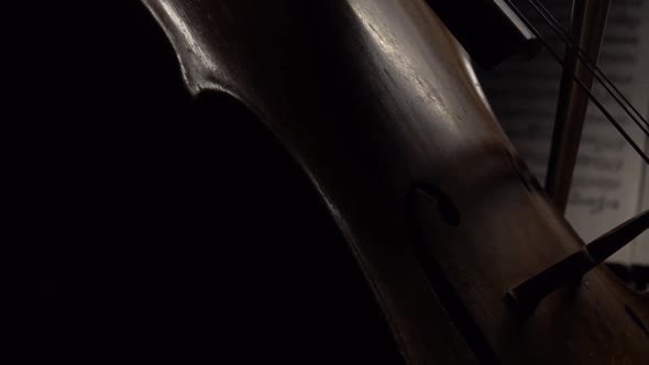 Cello in the Dark Bow Bow on the Strings Behind the Notes. Close Up. Side View