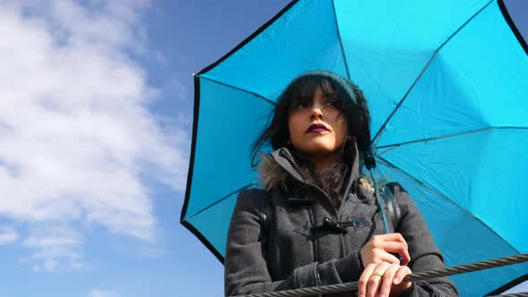 A beautiful woman with blue sky and weather umbrella as rain clouds from a storm pass overhead SLOW
