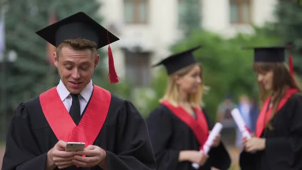 Male Graduate Reading Good News on Smartphone Before Ceremony, Astonishment